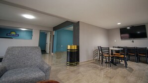 Eine Hotelhalle mit Sitzgelegenheit, einer Rezeption und einem an der Wand befestigten Fernseher.