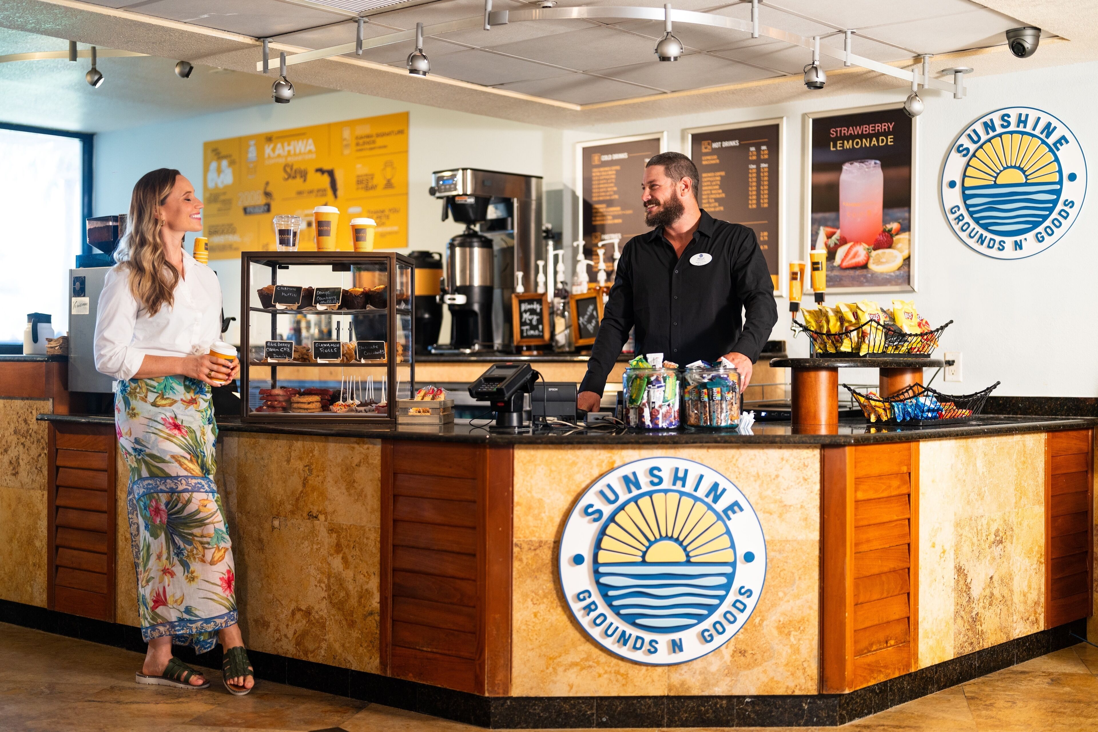 A coffee shop counter with a logo, a coffee machine, and a menu board.
