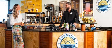 Un comptoir de café avec un logo, une machine à café et un panneau affichant le menu.