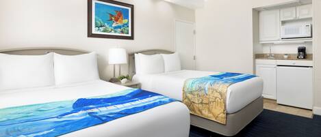 A hotel room with two beds, a kitchenette, and a framed picture on the wall.