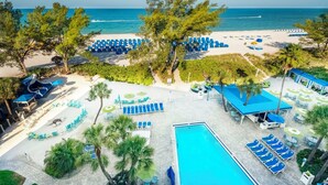 Een resort met een zwembad, ligbedden, parasols en vrij uitzicht op de oceaan.