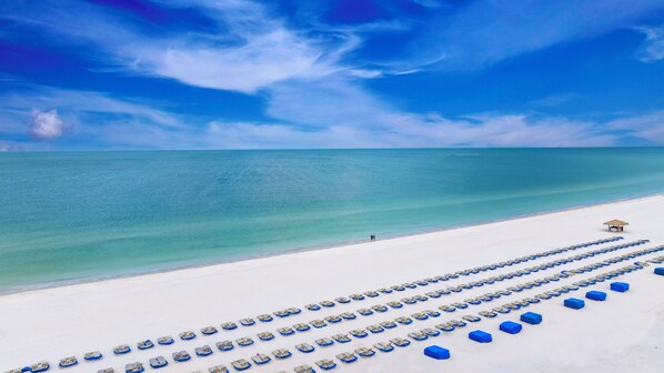 En la playa, arena blanca, sillas reclinables de playa, sombrillas