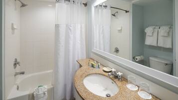 Un baño con bañera, un lavabo con encimera de granito, un espejo y una ducha con cortina.