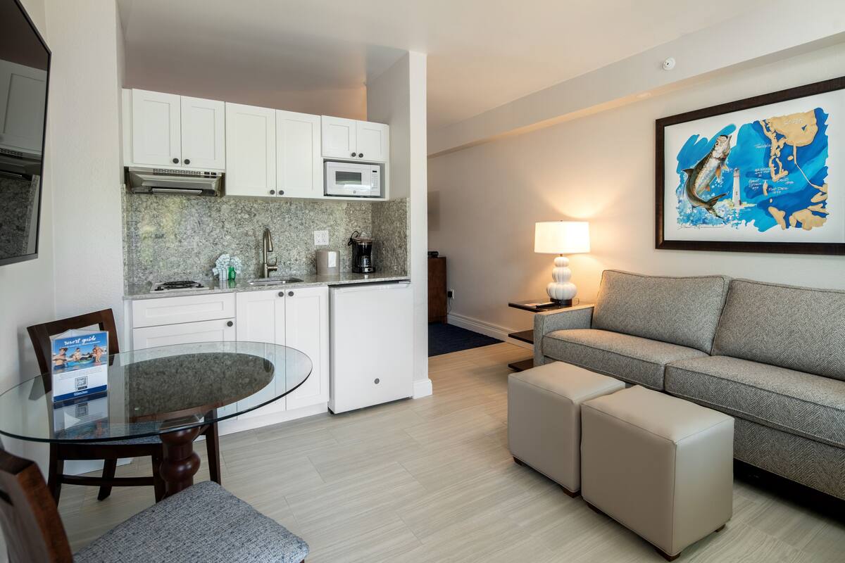 A compact living space with a kitchenette, a dining table, a sofa, and a framed map on the wall.