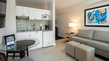 A compact living space with a kitchenette, a dining table, a sofa, and a framed map on the wall.
