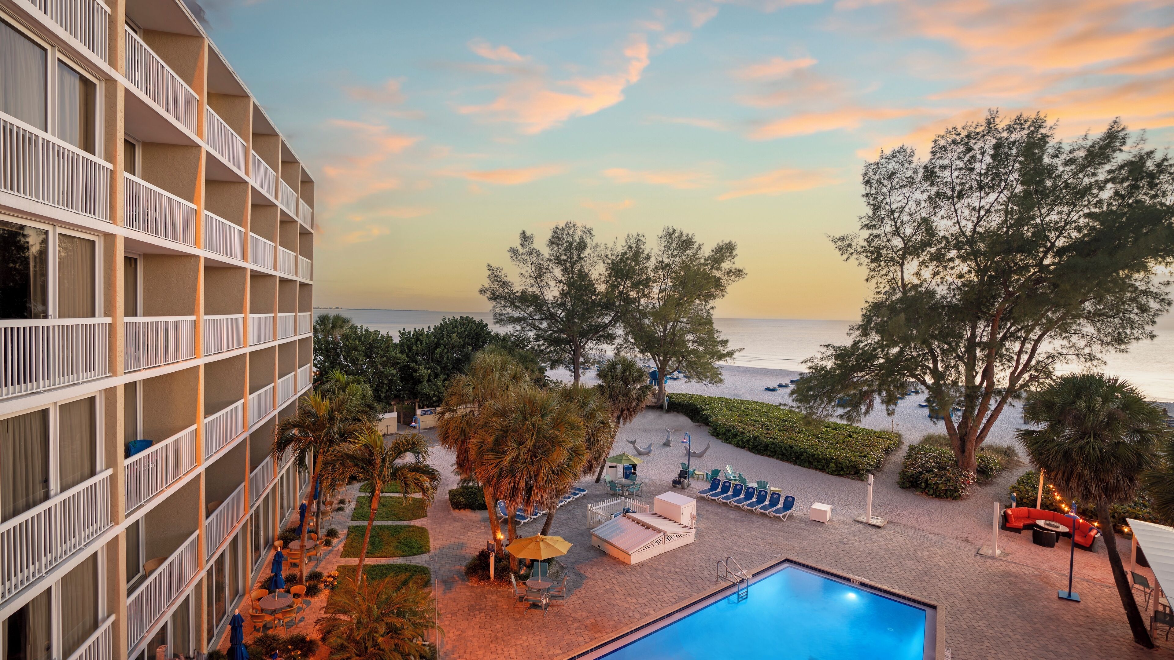 A hotel with a pool, outdoor seating, and a view of the sea.