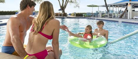 Ein Schwimmbad mit einer Familie und einem Kind in einer Schwimmhilfe.