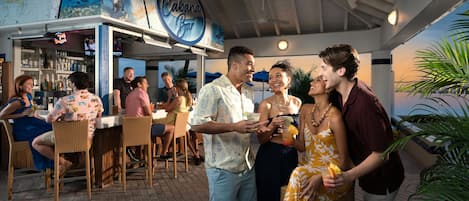 An outdoor bar area with a ceiling fan, wicker furniture, and a sign for 'Cabanas Bar'.