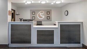A reception desk with a clock, a wall-mounted sign, and recessed lighting. - Comfort Inn Fergus Falls (Fergus Falls)