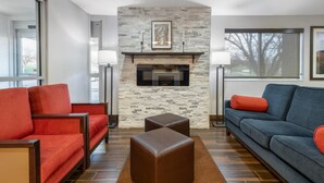 A modern living room with a stone fireplace, red and blue furniture, and large windows. - Comfort Inn Fergus Falls (Fergus Falls)