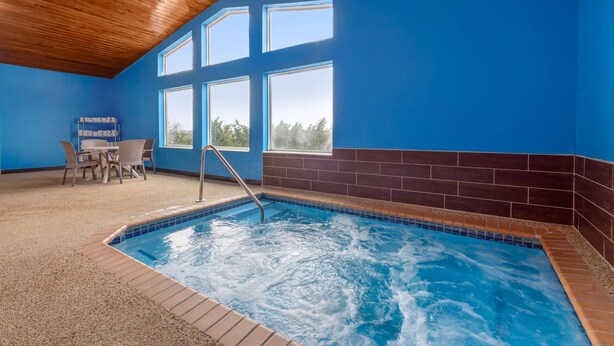 An indoor swimming pool with a wooden ceiling, blue walls, and a seating area with chairs and a table. - Comfort Inn Fergus Falls (Fergus Falls)