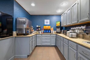 A kitchen with grey cabinets, a coffee machine, a refrigerator, and a sign indicating Seattle's Best ice cream. - Comfort Inn Fergus Falls (Fergus Falls)