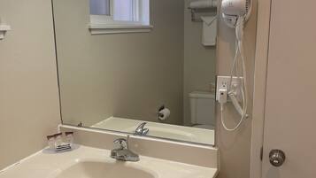 A bathroom with a white sink, a mirror, a hairdryer, and a window.