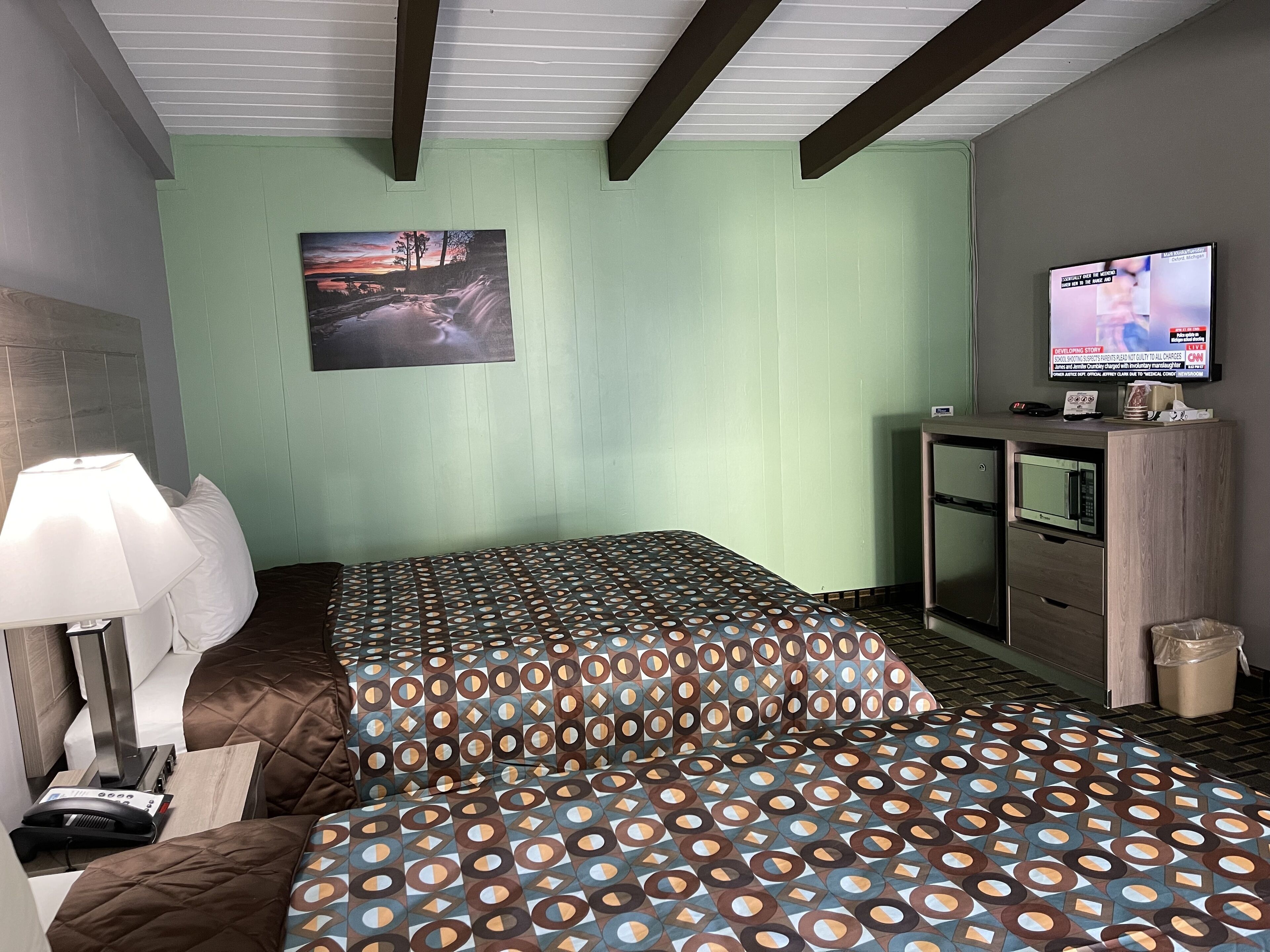 Une chambre d’hôtel avec un lit, un bureau, une télévision et un tableau au mur.