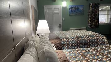 Una habitación con una cama, una lámpara de noche, una puerta y un cuadro en la pared.