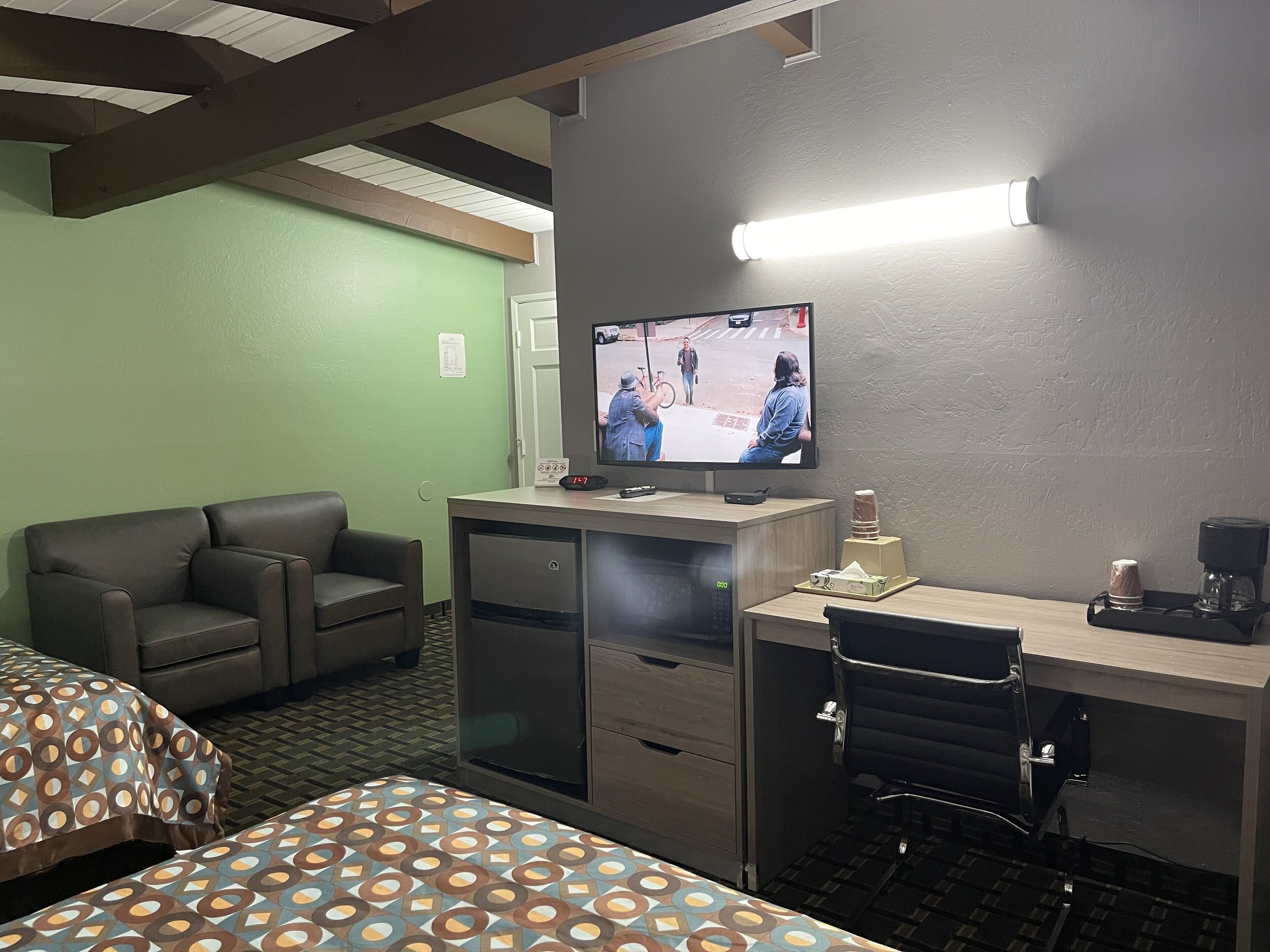 A hotel room with a bed, a desk with a computer, a television, and a coffee maker.