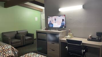 A hotel room with a bed, a desk with a computer, a television, and a coffee maker.