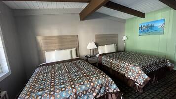 A hotel room with two beds, a nightstand, a lamp, and a painting on the wall.