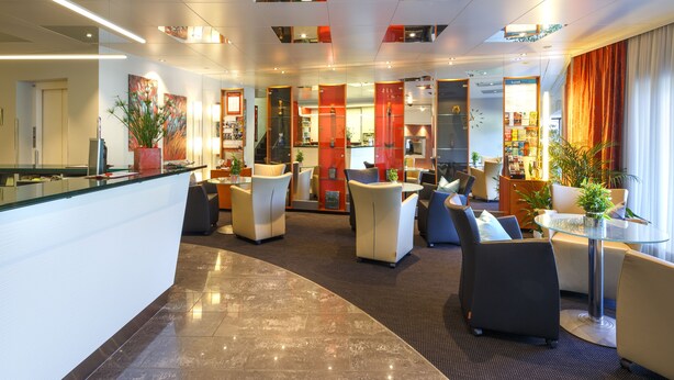 A modern hotel lobby with a reception desk, seating areas, and a visible staircase. - Hotel Metropol Basel (Basel)