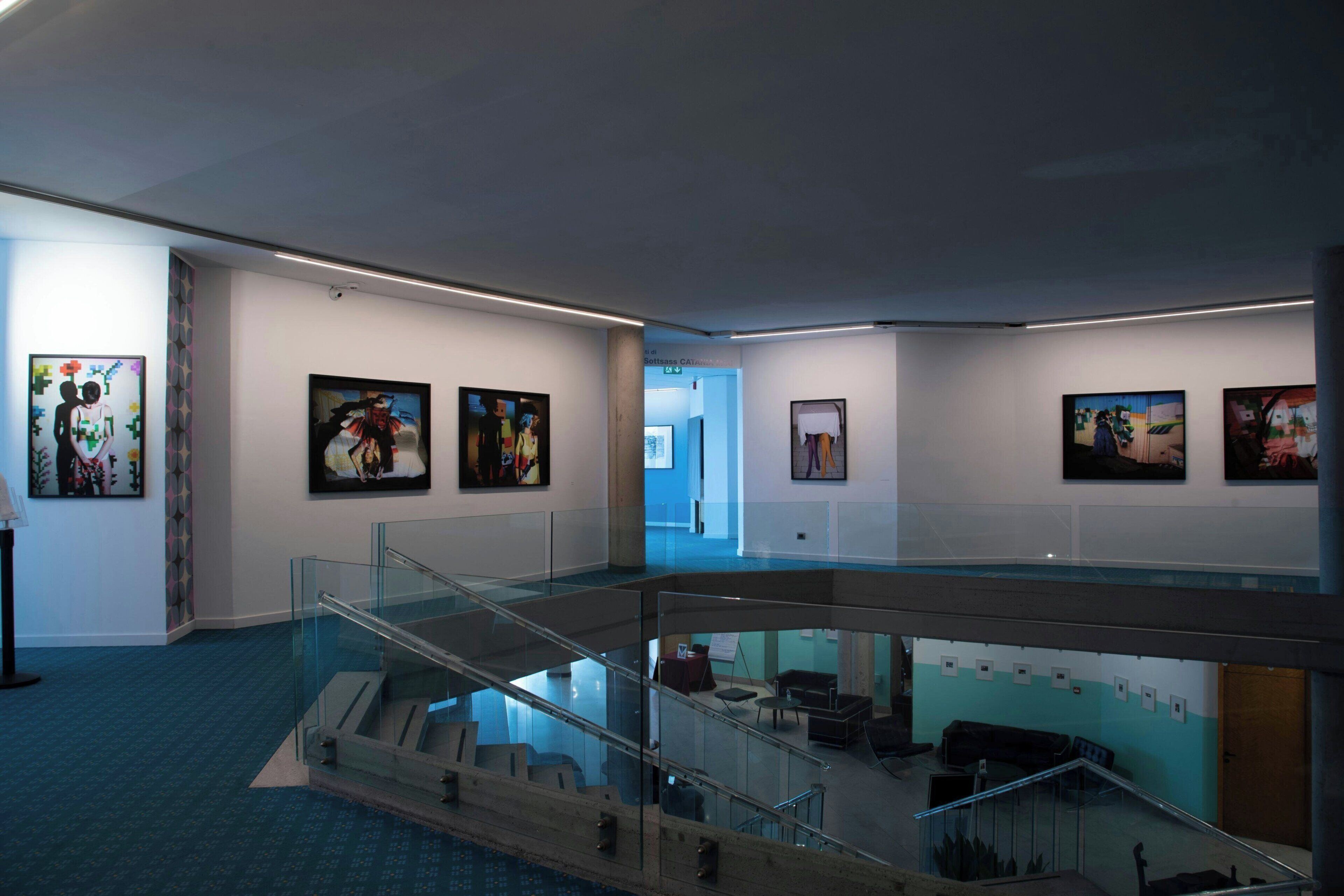 Ein modernes Interieur mit einer Glasstufenkonstruktion, Kunstwerken an den Wänden und einem Teppichboden in Blau.