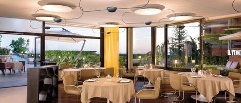 Un restaurante moderno con mesas redondas, manteles beige e iluminación contemporánea.