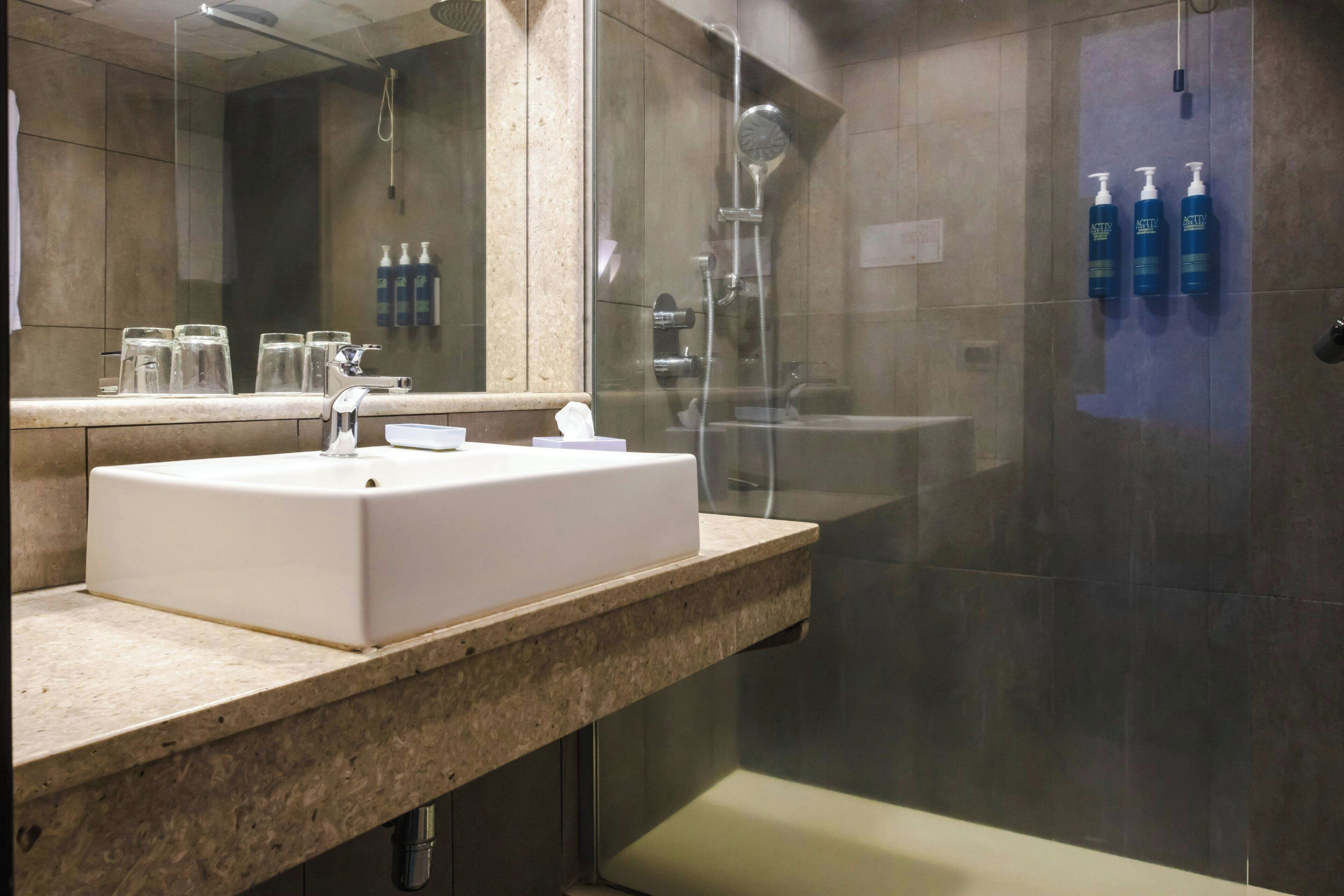 A bathroom with a white sink, a mirror, and a glass-enclosed shower area.