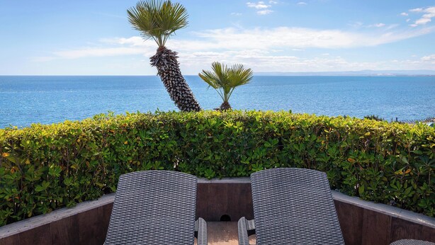 A terrace with wicker chairs and a view of the sea. - Four Points by Sheraton Catania Hotel & Conference Center (Aci Castello)