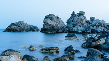 Una costa rocosa con grandes rocas y agua tranquila.