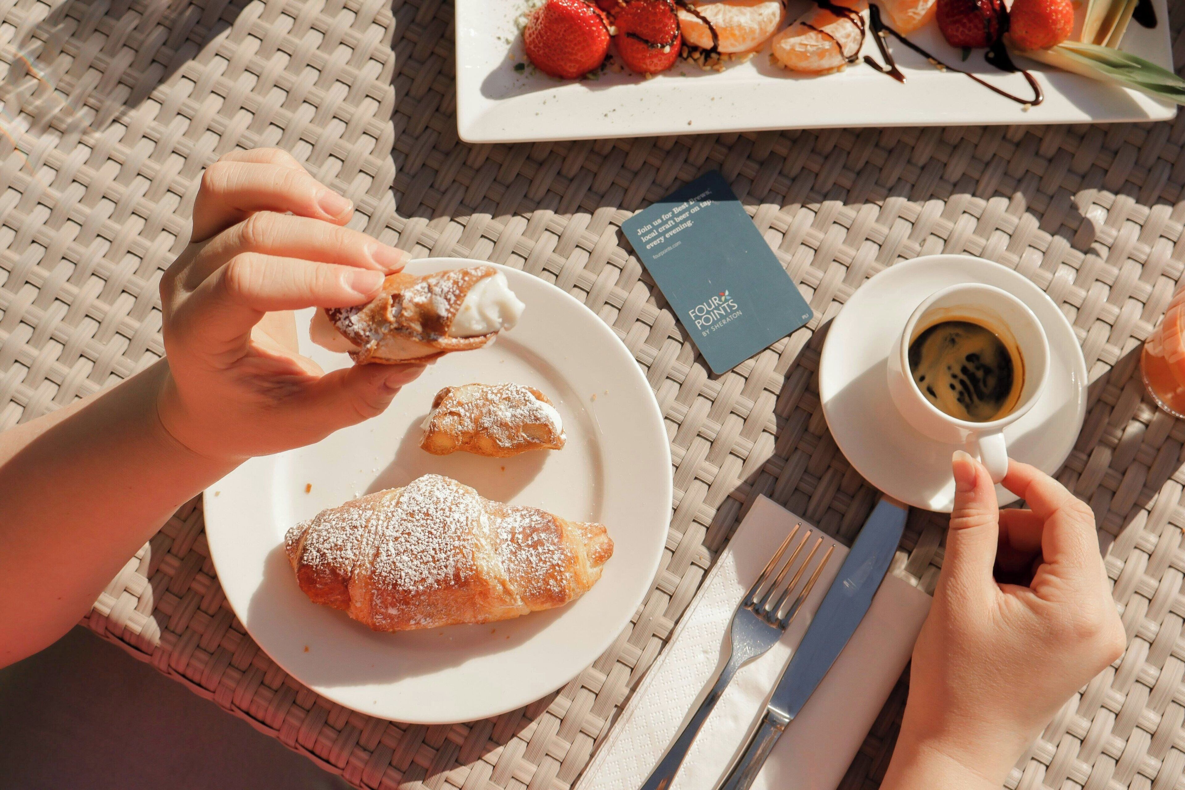 A table with a plate of pastries, a cup of coffee, and a menu.