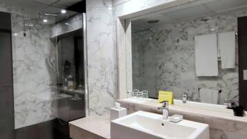 A modern bathroom with a marble vanity, a large mirror, and a glass-enclosed shower.