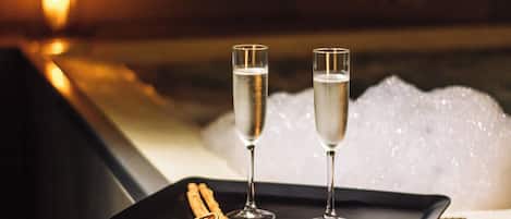 Two champagne flutes on a tray with cinnamon sticks, placed in front of a hot tub with bubbles.