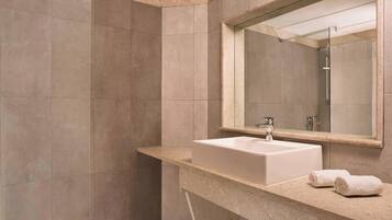 A modern bathroom with a large mirror, a sink, and a shower.