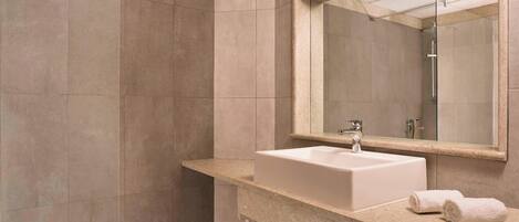 Een moderne badkamer met een grote spiegel, een wastafel en een douche.