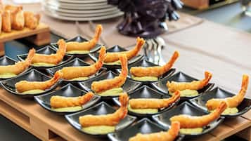 Una mesa de buffet con platos negros que contienen camarones fritos y una salsa verde.