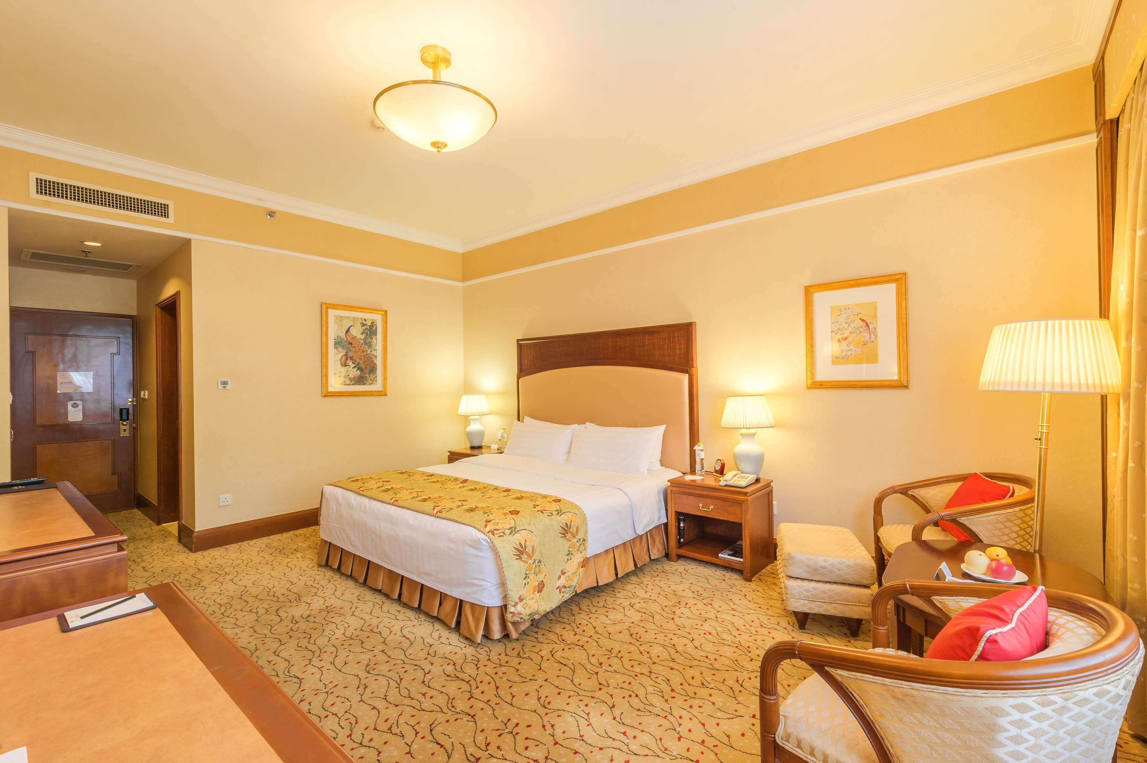 Une chambre d’hôtel avec un grand lit, des tables de chevet avec des lampes, une chaise et un bureau.