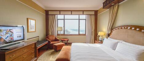 A hotel room with a bed, a desk, a chair, a TV, and a window with a view.