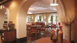 Uma sala de jantar espaçosa com pé-direito alto, portas em arco e um bar central.