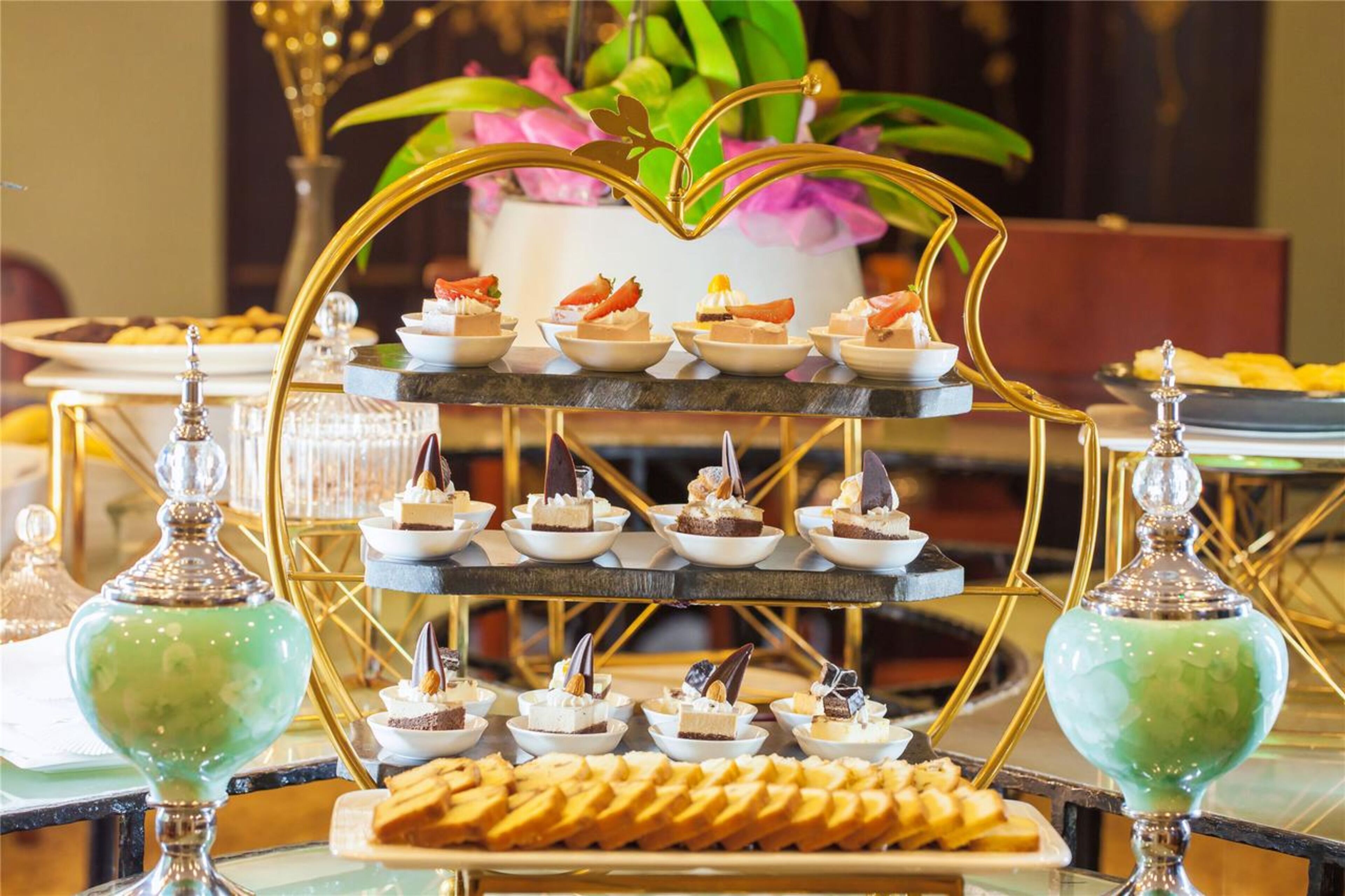 A multi-tiered dessert display with various sweets and pastries, accompanied by decorative glassware.