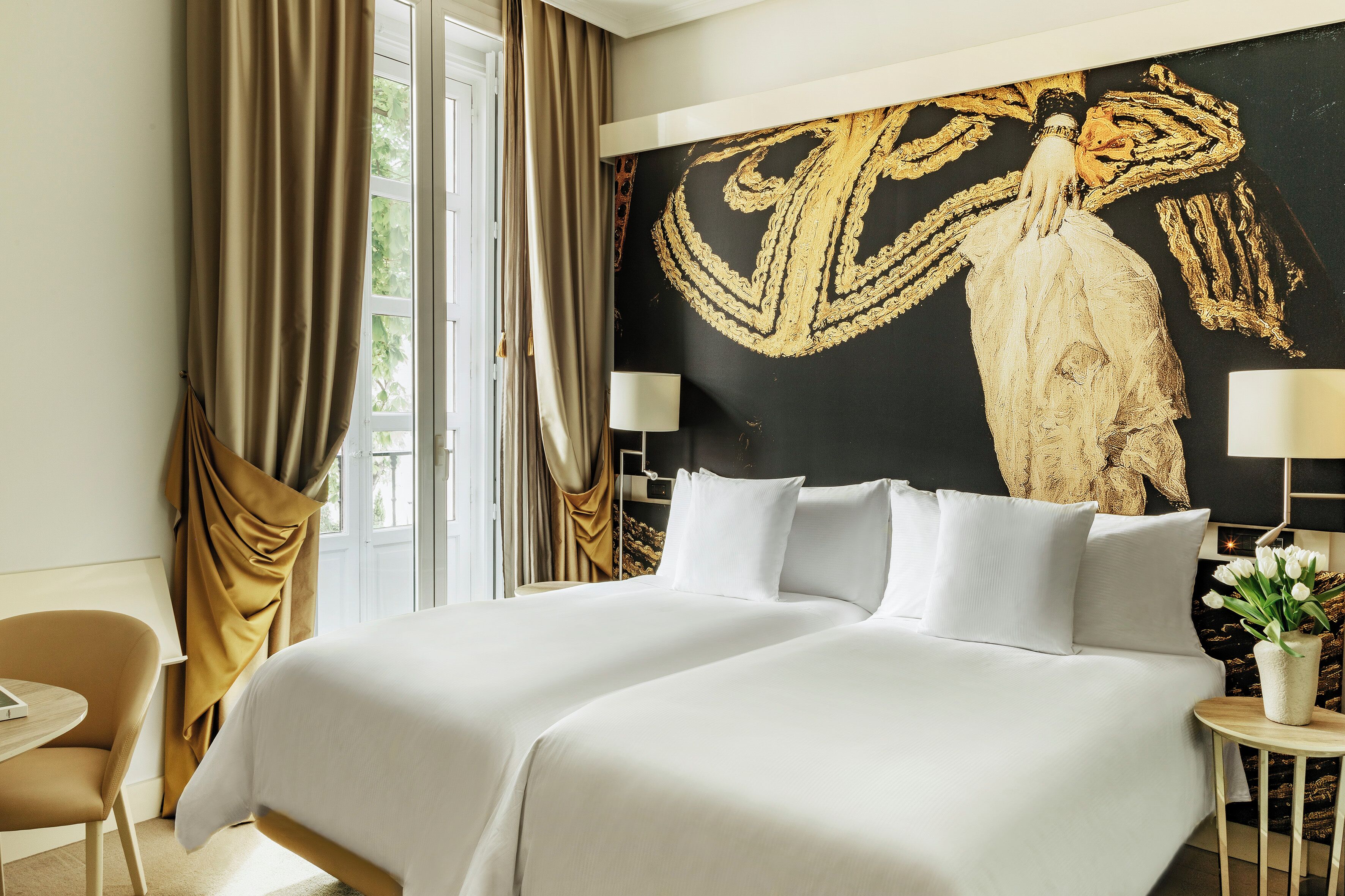 Habitación de hotel con una cama grande, un escritorio, una silla y un cuadro grande en la pared.