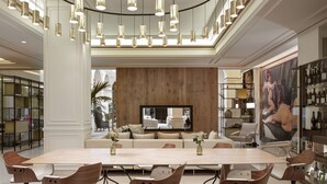 A spacious living room with a large wooden panel wall, a flat-screen TV, and a dining area with a long table and modern chairs.