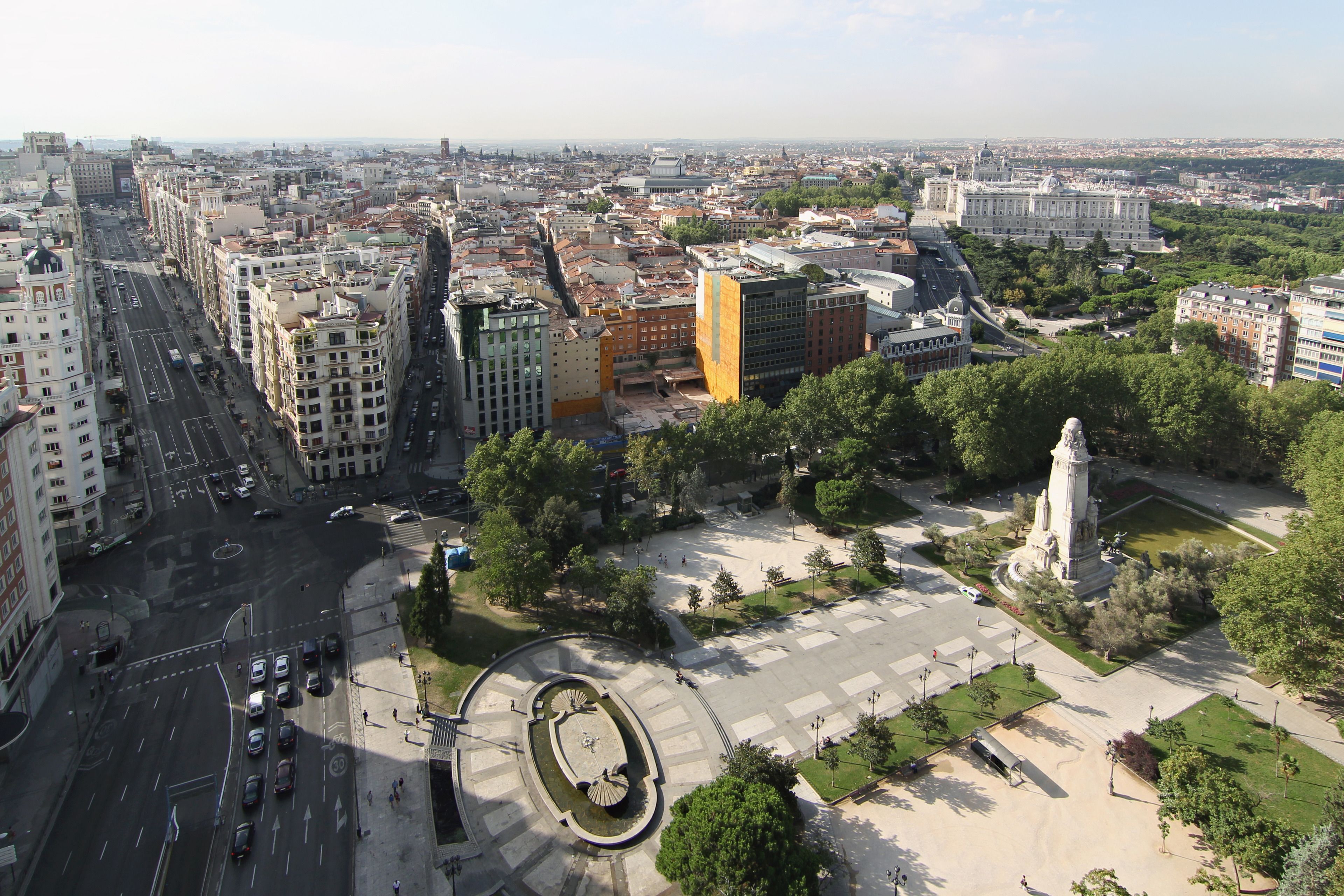 A cityscape with a central roundabout, surrounding buildings, and a statue.