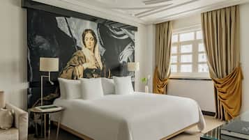 Habitación de hotel moderna con una cama grande, dos mesitas de noche, un escritorio y un cuadro abstracto de gran tamaño en la pared.