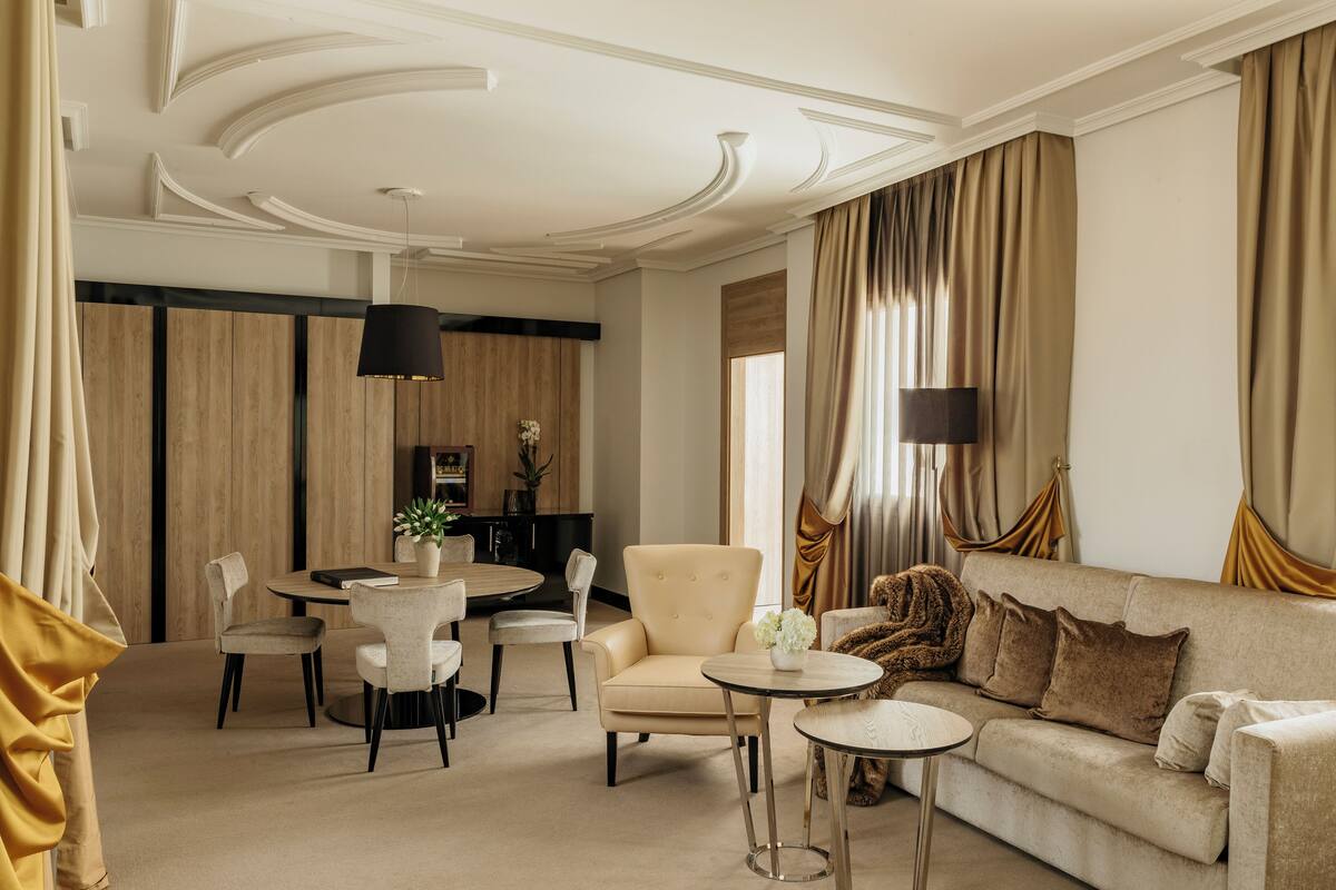 A spacious living room with a sofa, armchairs, a coffee table, and a dining area with a table and chairs.