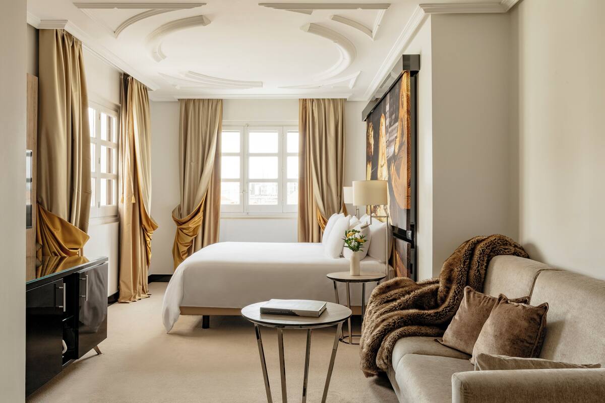 A hotel room with a bed, a sofa, a small table, and a TV.