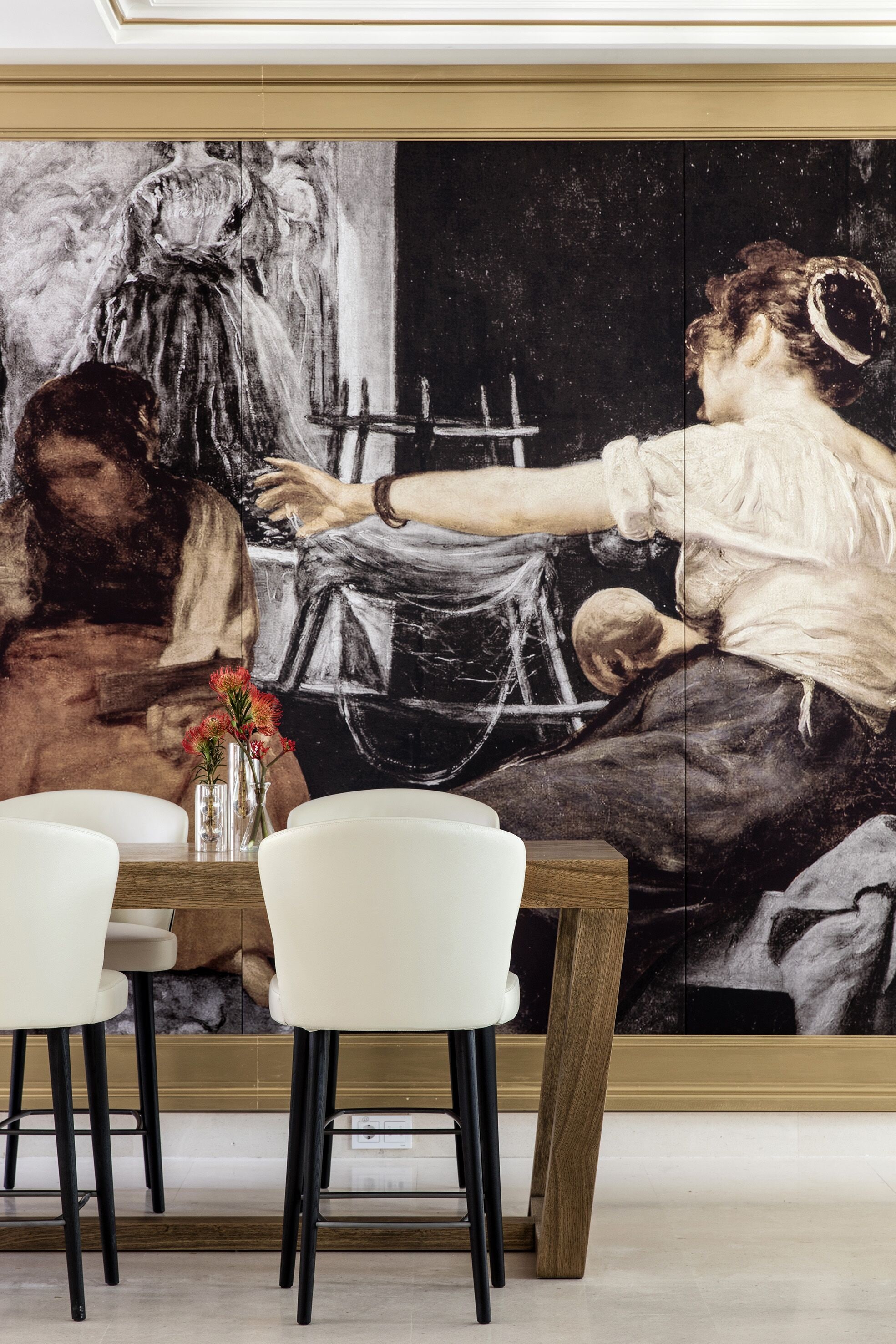 Un comedor con un cuadro grande en la pared, una mesa de madera y sillas blancas.