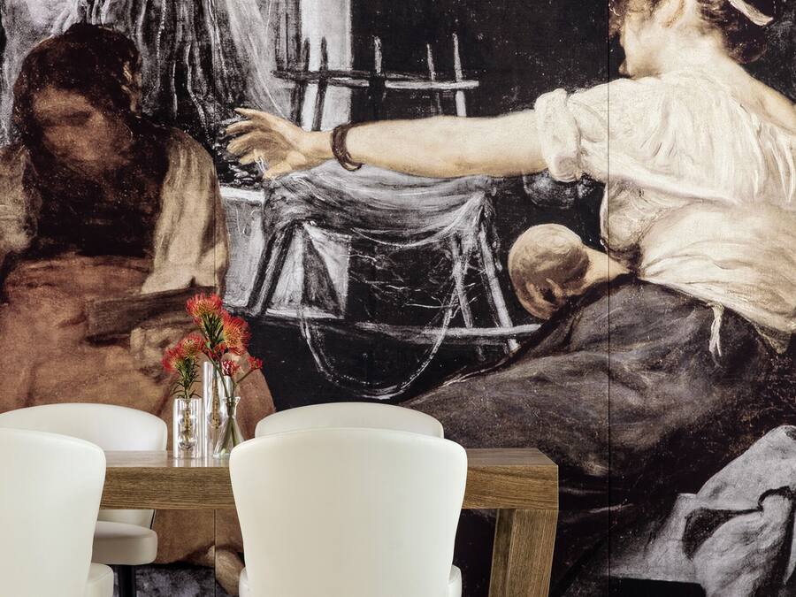 Un comedor con un cuadro grande en la pared, una mesa de madera y sillas blancas.