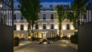 A courtyard with a fountain, outdoor seating, and a building with multiple windows and doors.