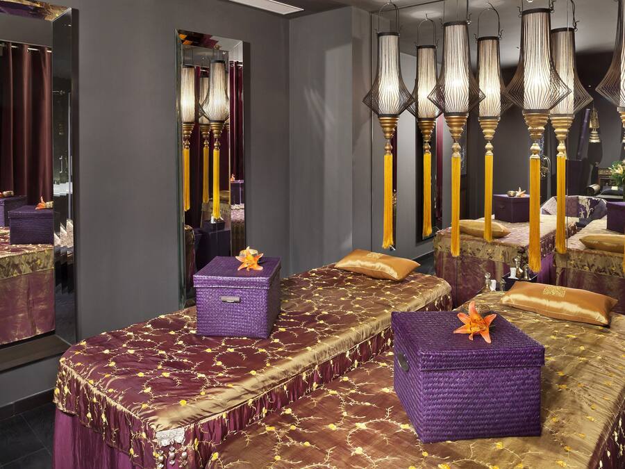 Una habitación con una cama grande, dos cajas moradas para guardar objetos y un espejo que refleja la habitación.