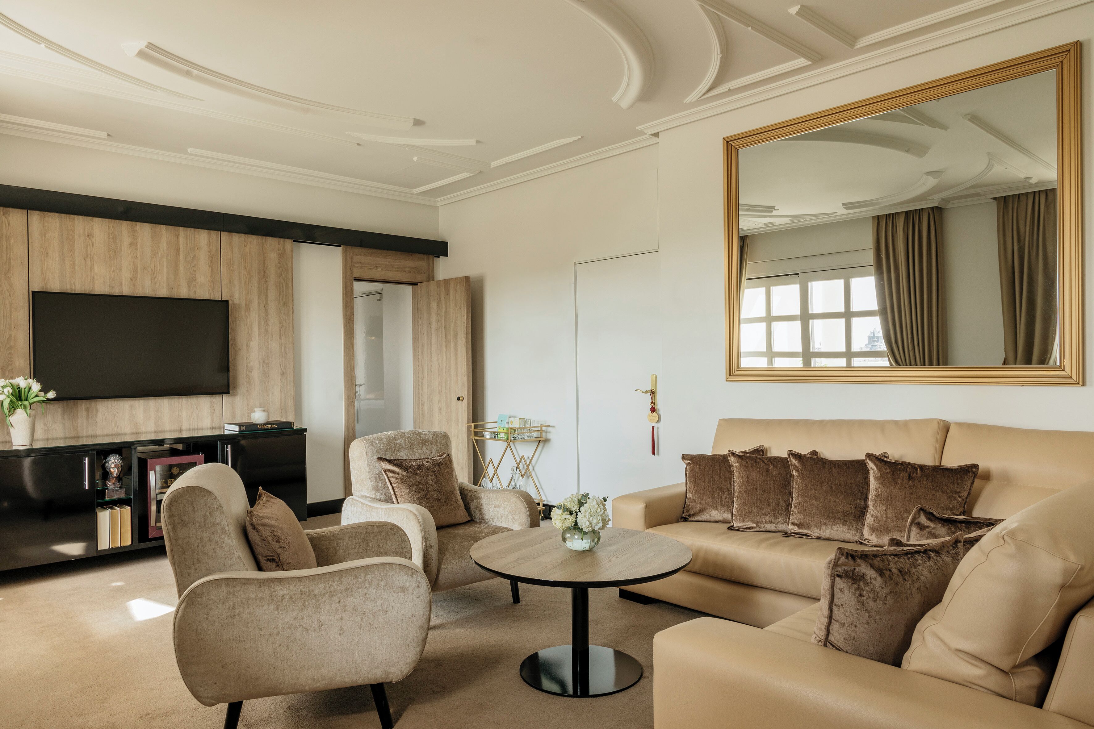 Una sala de estar moderna con sofá, sillones, una mesa de centro y televisión.