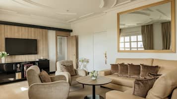 Una sala de estar moderna con sofá, sillones, una mesa de centro y televisión.